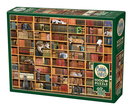 Cobble Hill The Cat Library 1000-piece jigsaw puzzle featuring curious cats exploring a cozy library filled with books, bookshelves, and warm reading spaces.