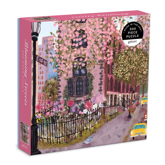 Galison Blooming Streets 500-piece jigsaw puzzle featuring charming city streets lined with colorful flowers, cafés, boutiques, and vibrant spring scenery.