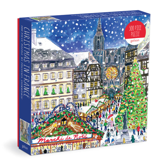 Galison Michael Storrings Christmas in France 500-piece jigsaw puzzle featuring festive French streets decorated for the holiday season.