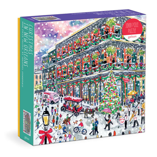 Galison Michael Storrings Christmas in New Orleans 1000-piece jigsaw puzzle featuring festive French Quarter streets decorated with Christmas lights, wreaths, holiday celebrations, and historic architecture.